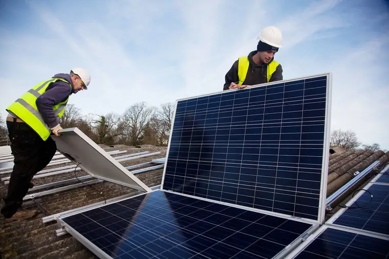 Installers fitting solar panels on a roof